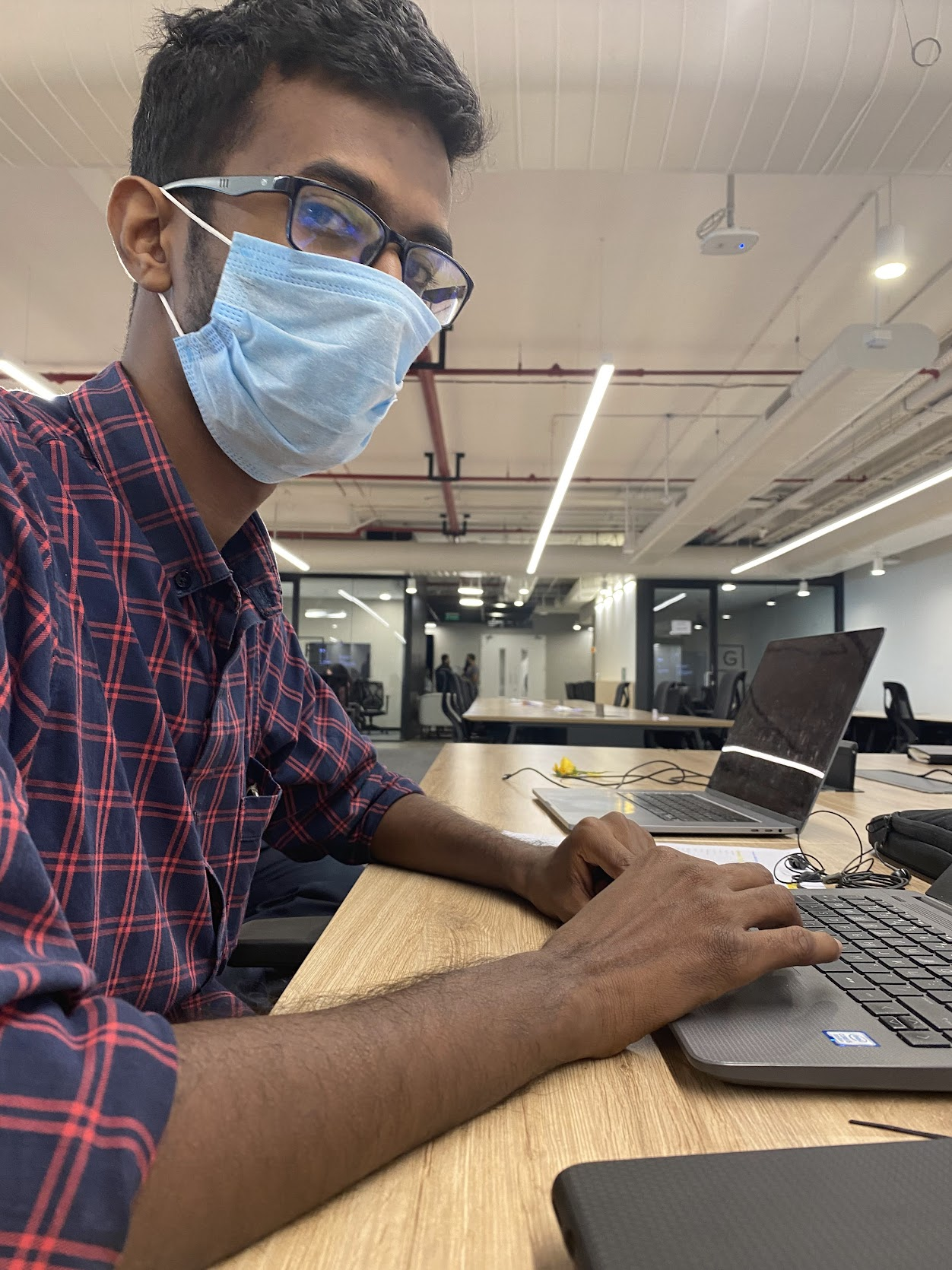Jibin Scaria at a coworking space, masked up and mid-typing.